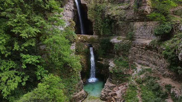 A man swimming in the Ujëvara e Peshturës waterfall in Albania.