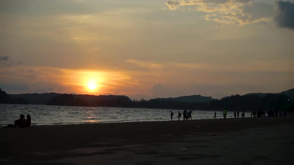 Ao nang beach time lapse as the sun sets over the mountains in the background as tourists and locals