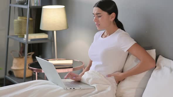 Latin Woman with Laptop Having Back Pain in Bed