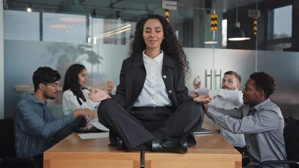 Young Hispanic Girl Sitting on Table in Office in Lotus Position Relaxing Feeling Calm Harmony