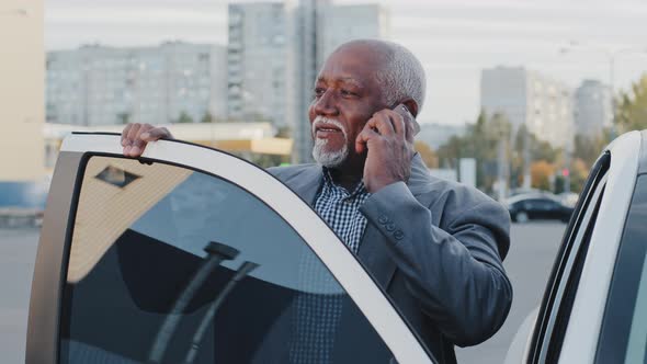 Mature African American Businessman Standing Outdoors Near Car Talking on Telephone Answering