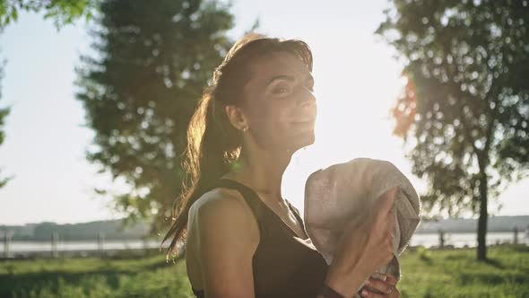 Athletic Woman Towels Off Sweat After Exercising in Park on Sunny Day