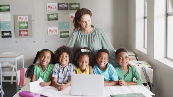 Video of happy caucasian female teacher and class of diverse pupils smiling at camera