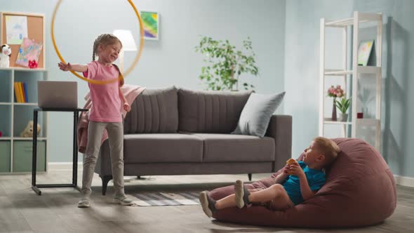 Blond Hair Children Relaxing in Bright Room Smiling Girl is Spinning Hula Hoop