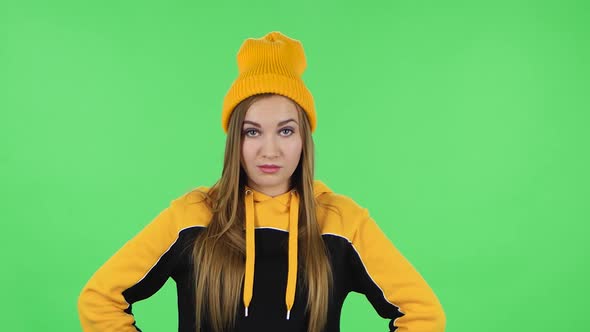 Portrait of Modern Girl in Yellow Hat Stands Angrily and Crosses Her Arms Over Her Chest. Green