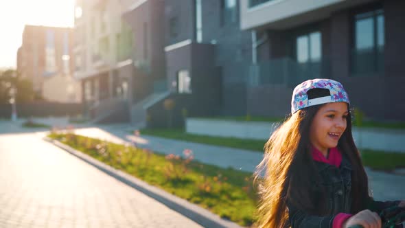 Brunette Girl Riding a Scooter at Sunset in Her Area