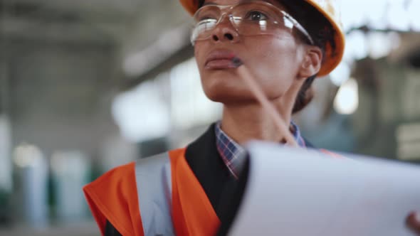 Concentrated African woman engineer in uniform writing in notebook