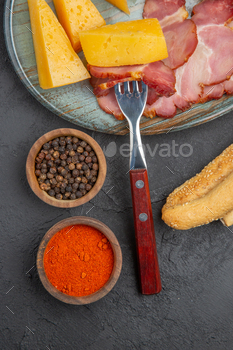 Vertical view of delicious sausage and cheese slice on a blue plate peppers on a dark background / Photodune, Misc