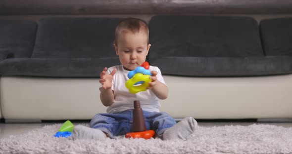 Cute Little Baby Boy Playing with Colorful Pyramid Toy at Home