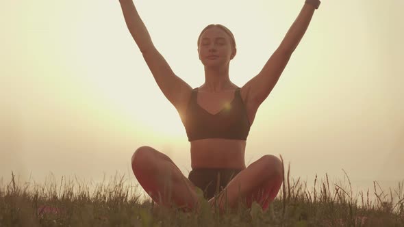 Young Woman Meditating By the Sea at Sunset