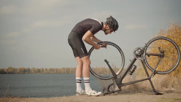 Cyclist Checking His Bike After Triathlon. Triathlete Fixes His Bicycle After Breakdown.