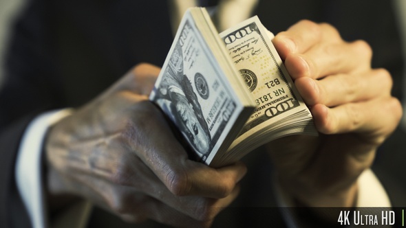 4K Businessman Flipping Through $100's of US Dollars Closeup