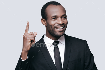 wear pointing up and smiling while standing against grey background