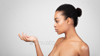 erican Lady Looking At Invisible Skincare Product In Her Hand Posing Shirtless Over Gray Background. Panorama, Studio Shot, Side View