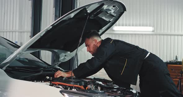 Sweating Mechanic Guy in a Garage Working Very