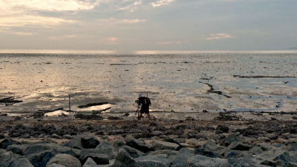 Silhouette asian cameraman photography low tide beach with sunset over sea on beach