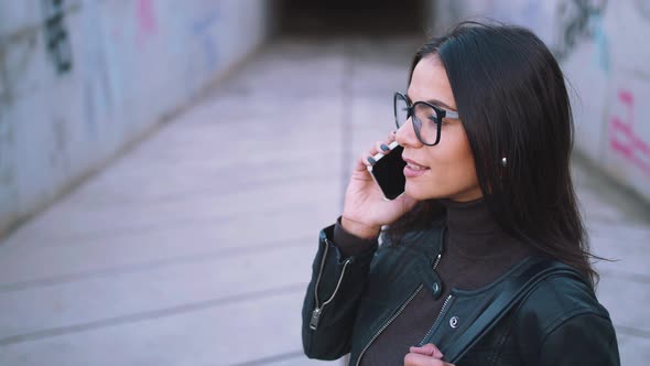 Young Stylish Woman in Glasses Talking on Phone Outdoors