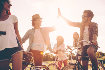  standing near their bicycles on the road while two men giving high five