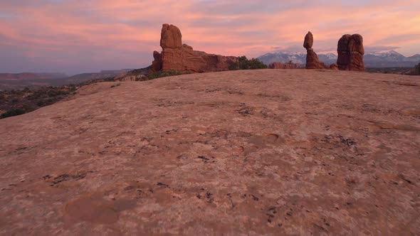 Walking towards Balanced Rock during colorful sunset in Arches