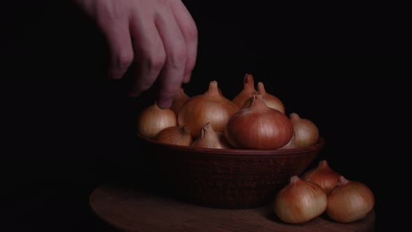 Pile of Whole Bulbs of Raw Onion in Ceramic Bowl on Table