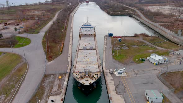 High quality, 4K aerial view of a bulk carrier ship maneuvering inside a canal.