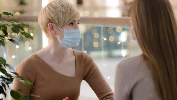 Two Women Friends Mother with Teenage Daughter Talking in Cafe Wear Medical Face Protective Masks