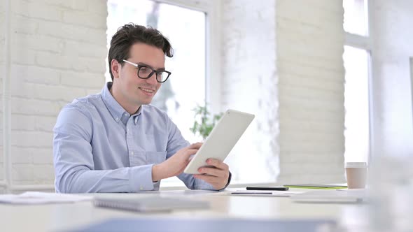 Cheerful Working Young Man Using Tablet in Modern Office