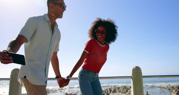 Couple taking selfie while walking on beach promenade 4k