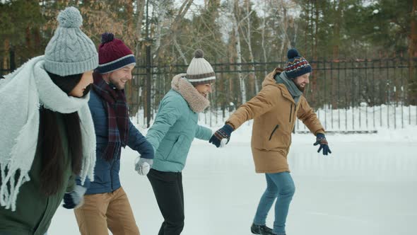 Joyful Men and Women Ice-skating in Park Laughing Having Fun Together on Winter Day