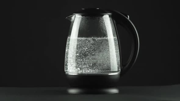 In a Electric Kettle with Transparent Glass Walls, Water Boils. Black Background.