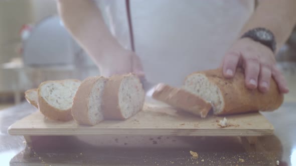 Baker is Cutting Baked Dutch Bread with Raisins and Dried Apricots with Knife
