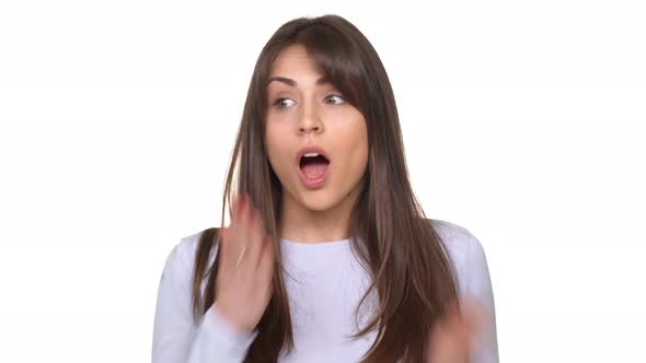 Cute Young Caucasian Brunette Female Covering Her Mouth with Arm and Standing Surprised Over White