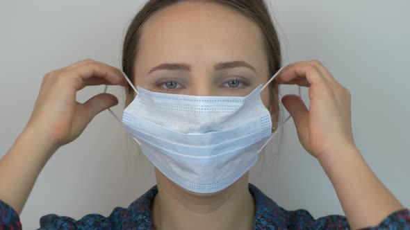 Portrait of female face putting on protective medical blue mask for virus infection prevention