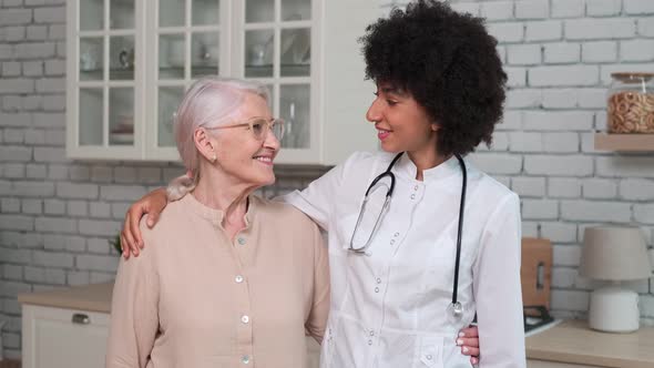 Afro American Woman Doctor and Patient Senior Woman Standing and Smiling at Home