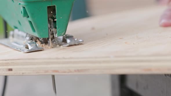 Sawdust Flies Off a Metal Blade As the Jigsaw Cuts Into a Sheet Plywood Workpiece