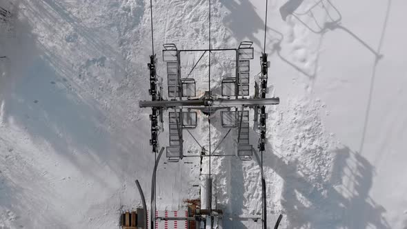 Aerial Top View of Ski Lift for Transportation Skiers on Snowy Ski Slope. Drone Flies Over Chair