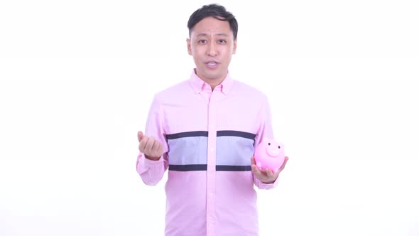 Happy Japanese Businessman Talking While Holding Piggy Bank