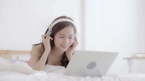 Beautiful young asian woman happy earphone listening music with relax and enjoy in the bedroom.