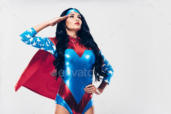 utiful young woman in superhero costume looking away and holding hand near head while standing against white background
