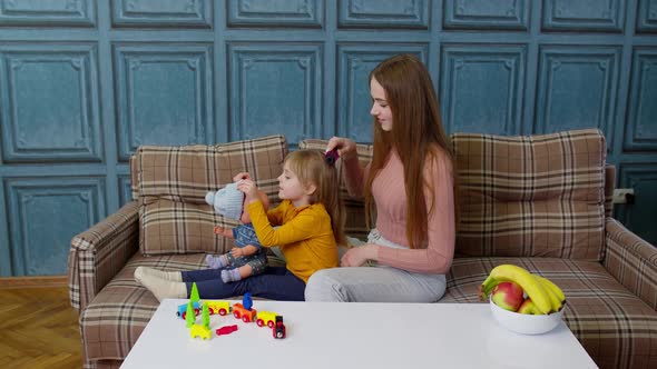 Mother Taking Care Brushing Hair of Daughter Child Girl in Living Room Kid Playing with Toy Doll