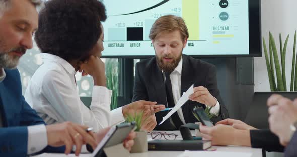 Boss Discussing Report together with Female Black-Skinned Subordinate During Meeting in Office