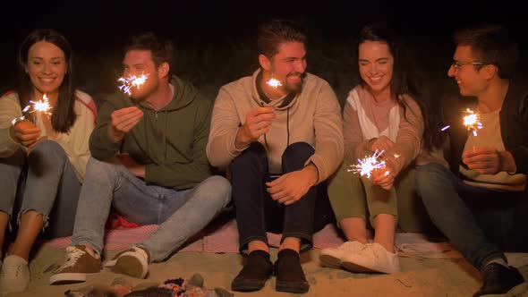 Happy Friends with Sparklers at Camp Fire at Night