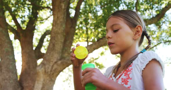 Girl blowing bubbles through bubble wand