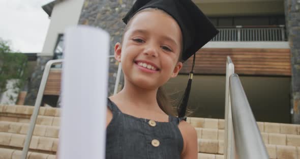 Video of happy caucasian girl wearing graduation hat and holding diploma