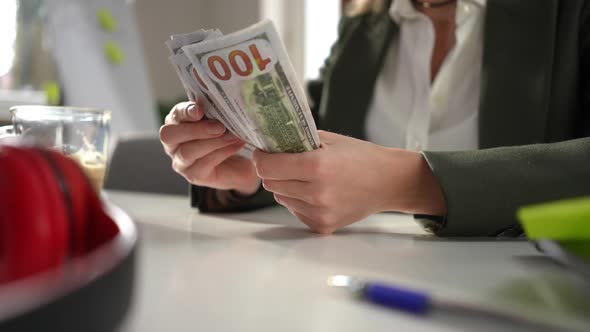 Female Caucasian Hands Counting Cash Dollars Sitting at Table Indoors