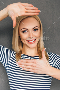 rame and looking at camera with smile while standing against grey background