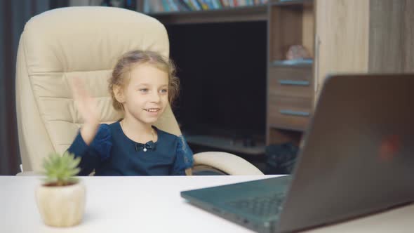 A 6Yearold Girl Wearing a Medical Mask Makes a Video Call on a Laptop