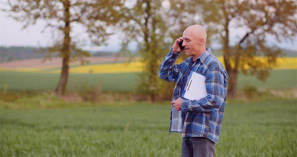 Farmer Talking on Mobile Phone While Working in a Field Agriculture