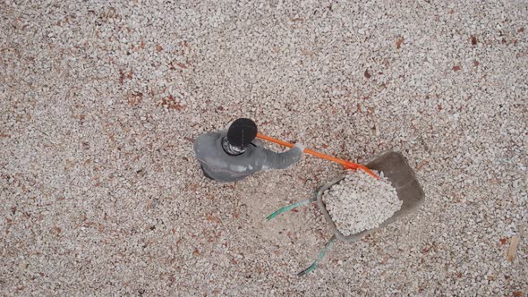 Top View. A Man Uses a Shovel To Pick Up Rubble in a Wheelbarrow. Construction