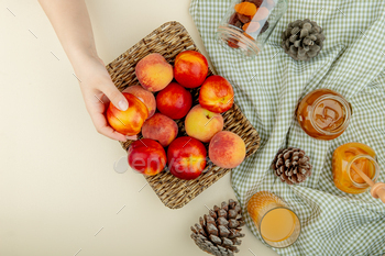 top view of woman hand holding basket plate of peaches with plum jam, peach juice, raisins and / Photodune, Misc